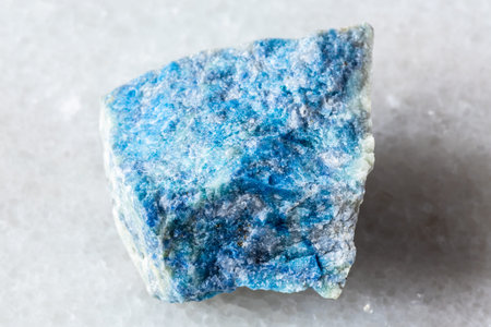 sample of rough lazurite (lapis lazuli) mineral on white marble background close up from Pamir