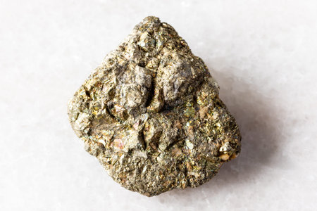 sample of uncut pyrite mineral on white marble background close up