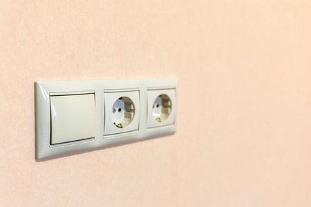 installed electrical sockets on light brown painted wall of room during apartment renovation