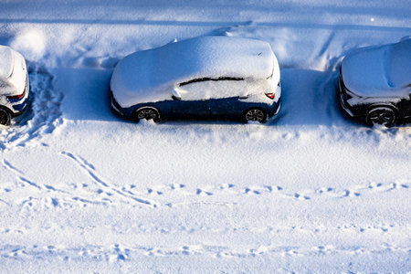 aerial view of snow-covered parked cars on street after snowfall on sunny winter day