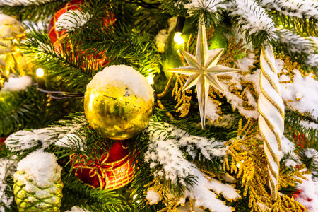 various toys on outdoor snow-covered christmas tree close up in night
