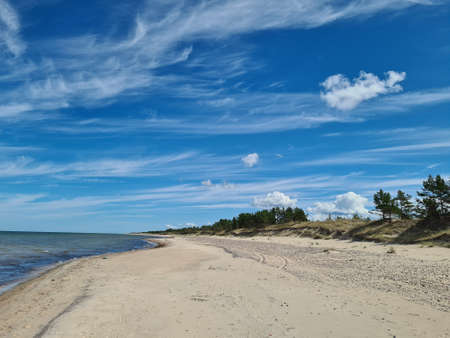 A lonely beach with blue sky and light cloudsの写真素材
