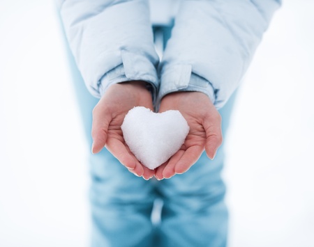 Heart made of snow in female handsの写真素材