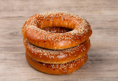 Baked bagels sprinkled with sesame seeds on wood table