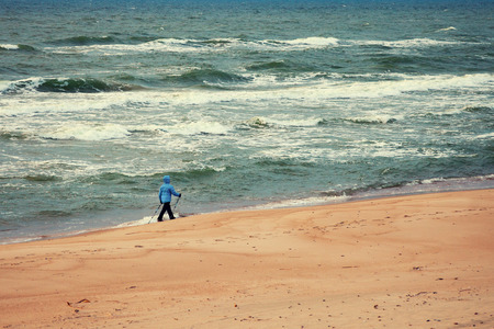 Woman on the beach. Nordic walker on the beach with stormy seaの写真素材
