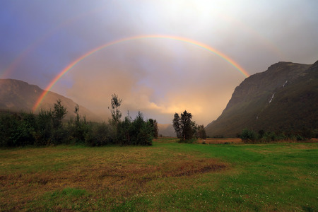 Rainbow after rain over mountainの写真素材
