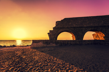 Remains of the ancient Roman aqueduct in ancient city Caesarea at sunset. Israel.の写真素材