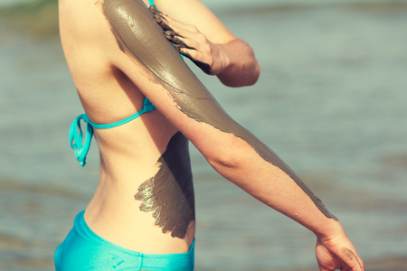 Woman smearing mud mask on the bodyの写真素材