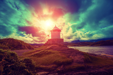 lighthouse against dramatic cloudy sky during sunsetの写真素材