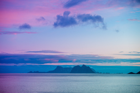 An island with a mountain on the horizon. Beautiful landscape, blue sky with clouds and sea. Wild nature Norway, seascape.の写真素材