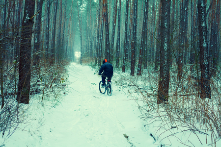 Man ride bicycle in snowy winter in the forestの写真素材