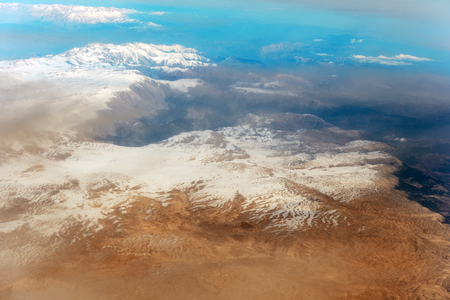 Aerial view through clouds. Airplane view of mountains with glacierの写真素材