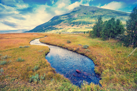 A narrow winding mountain river in the valley. Beautiful nature of Norwayの写真素材