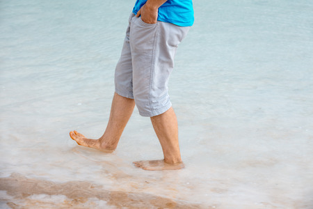 A man walks barefoot on the salty beach of the Dead Seaの写真素材