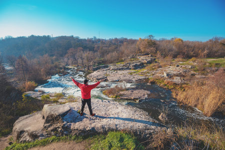 A human standing on the rock of canyon with hands in the air in autumn