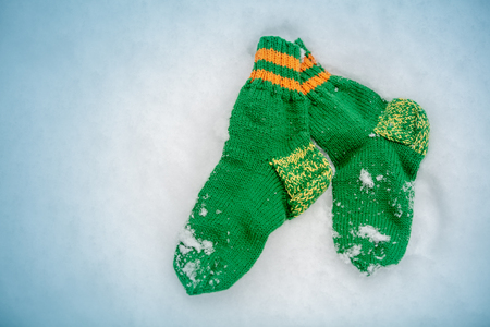 Green knitted socks lying on the snow in winterの写真素材