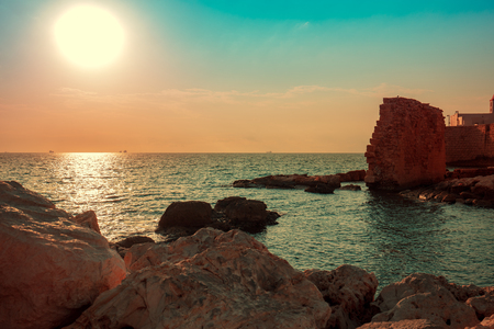 Rocky coast in the evening. The ruins of the ancient city. Sunset over the seaの写真素材
