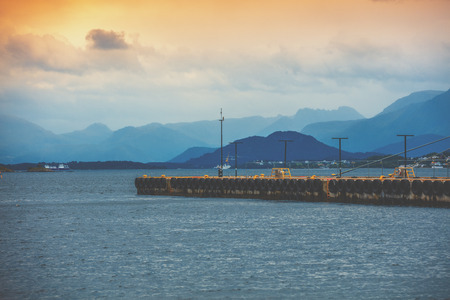 Bay in the evening light. Pier in the sea and mountains on the horizon. Alesund, Norway, Europeの写真素材