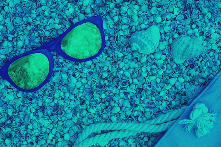 Beach scene. Sunglasses and beach bag lying on sea coquina shellsの写真素材