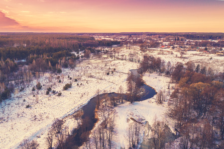 Aerial view of rural landscape at sunset. Top view of a narrow winding river and countryside in a snowy winter;の写真素材