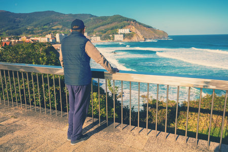 A man standing on the embankment and looking at the ocean and the beautiful bay. Bakio, Biscay,...
