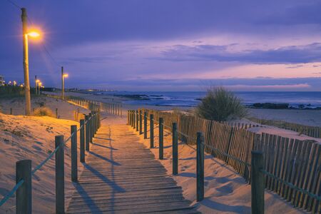 Wooden terrace on the sandy seashore after sunset. Beautiful beach in the evening. Coast of the Atlantic Ocean near Porto, Portugalの写真素材