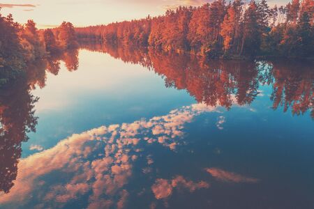 Magical sunrise over the lake with a beautiful reflection on the water. Tranquil lake in the early morning. Natural landscapeの写真素材