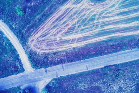 Aerial view of geometric wheat fields. Abstract natural background. Country road in the filelds. Blue coloredの写真素材