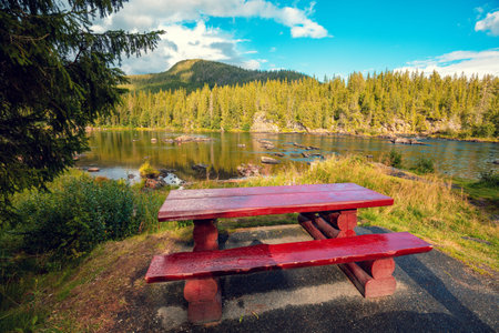 Mountain river. Wooden table and benches near the river. The place for relaxing on the riverbank. Beautiful nature of Norwayの写真素材