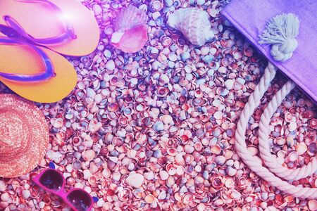 Beach scene. Women's accessories. Sunglasses, sun hat, flip flops sandals and beach bag lying on a shellの写真素材