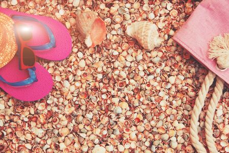Beach scene. Women's accessories. Sunglasses, flip flops sandals and a beach bag lying on a seashell shellの写真素材