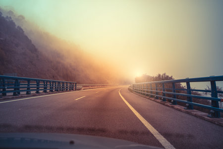 View of the overpass through the windshield. Beautiful misty morning landscape with a highway, bridge, and dramatic cloudy sky. Asturias, Spainの写真素材