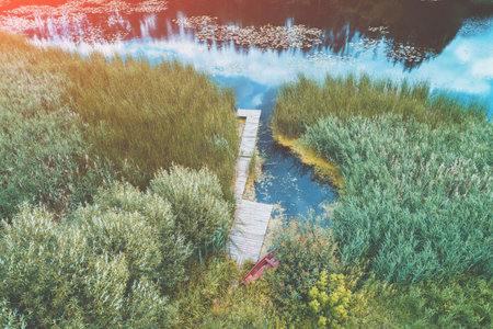 Top view of a lake in the countryside on a sunny summer day. Wooden pier on the lake
