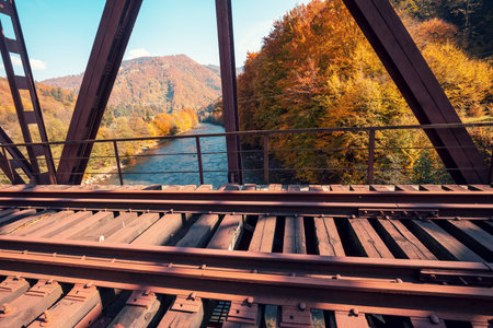 Old railway on the bridge over the mountain river in autumn