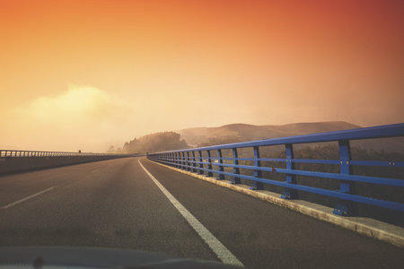 View of the bridge over the river through the windscreen. Beautiful evening landscape with the...