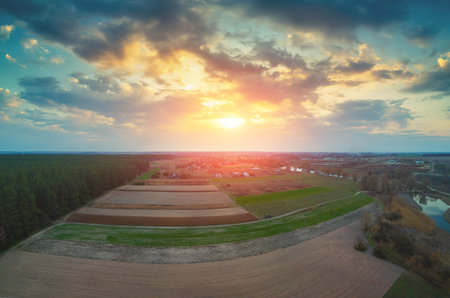 Sunset in the countryside. Rural landscape in early spring. Aerial view of the forest, arable...