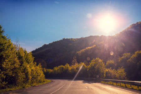 Driving a car on a mountain road. Empty road on a sunny day. View from the car of mountain landscapeの写真素材