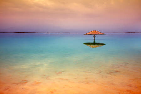 The minimalist landscape before sunrise. Sun umbrella in the water. Beautiful Dead Sea. Color gradientの写真素材