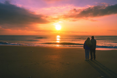 Seascape in the evening. Young couple stands on the beach in the evening and looks at the sunset