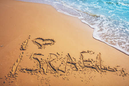 The words I love Israel on the beach sand. Inscription I love Israel on seashore with waveの写真素材