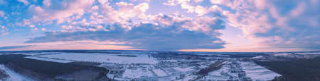 Aerial view of winter snowy countryside at sunset. Horizontal panoramaの写真素材