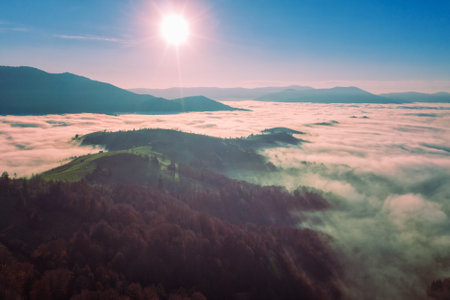 Fantastic view of the tops of the mountain ridge above the clouds at sunriseの写真素材
