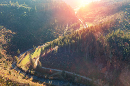 Aerial view of a road along a meandering river in a mountain gorge on a sunny day. Mountain view in autumn. Beautiful natural landscape. Carpathian mountains. Ukraine;の写真素材