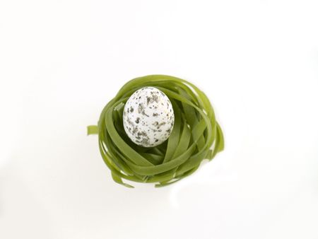 Green pasta nest with egg, white backgroundの写真素材