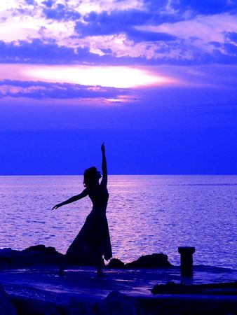 Young woman standing at ballerina pose, sunset at the backgroundの写真素材