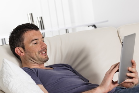 man using tablet pc on sofa at homeの写真素材