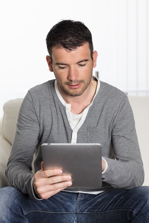 man using tablet pc sitiing on sofa at homeの写真素材