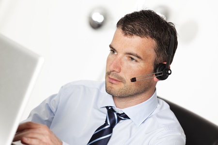 man working with headset and computer in officeの写真素材