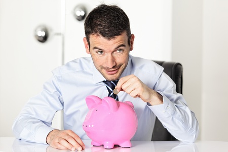 man with coin and pink piggy bankの写真素材