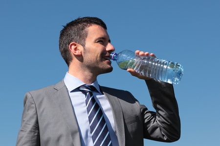 businessman drinking water with bottle and blue skyの写真素材